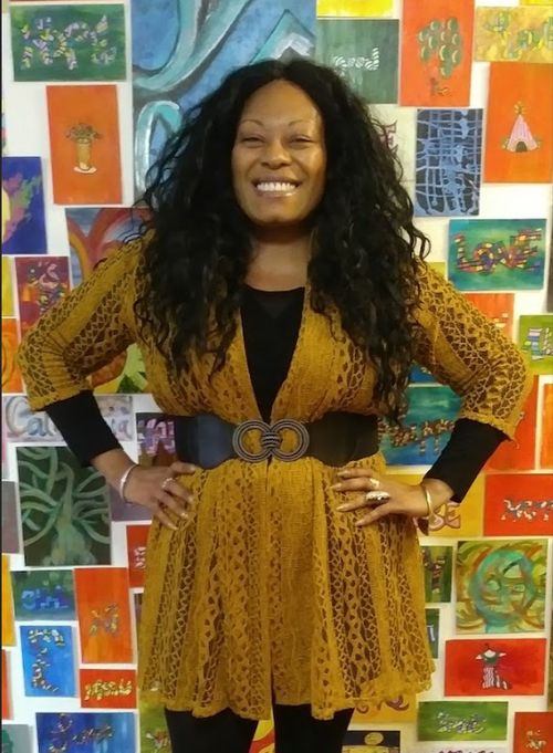 Nadine stands in front of a wall covered in artwork.