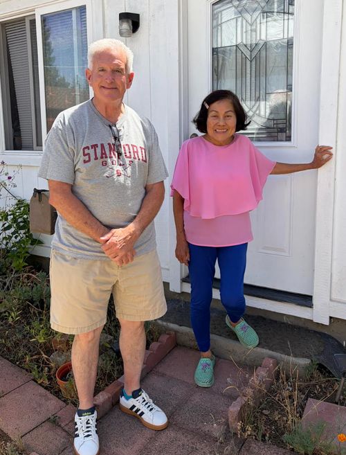 Judy stands with Scott in front of the door to a home.