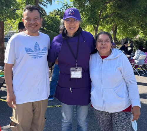 Three adults standing in a row looking at the camera.  The center person is wearing a United Effort uniform.